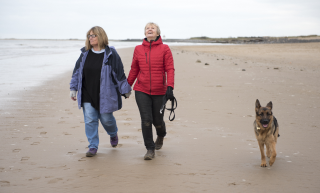 Couple-walking-dog-on-beach